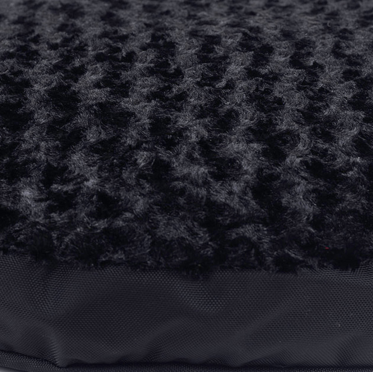 Close-up of black swirl plush fabric over a dark nylon dog bed edge