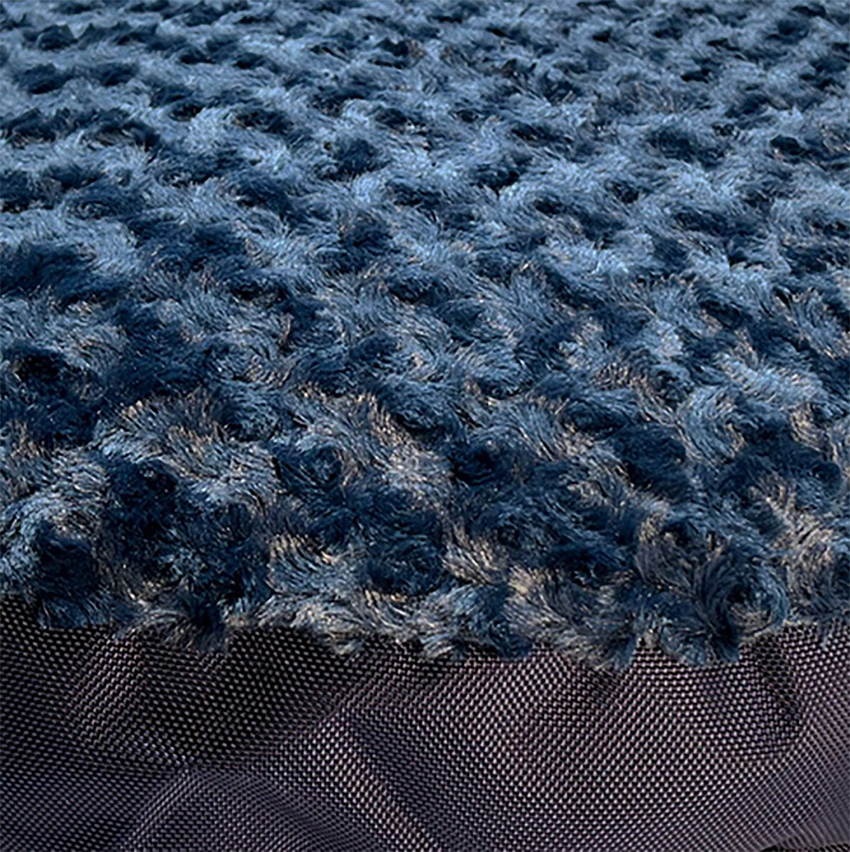 Close-up of midnight blue swirl plush fabric over a dark nylon dog bed edge