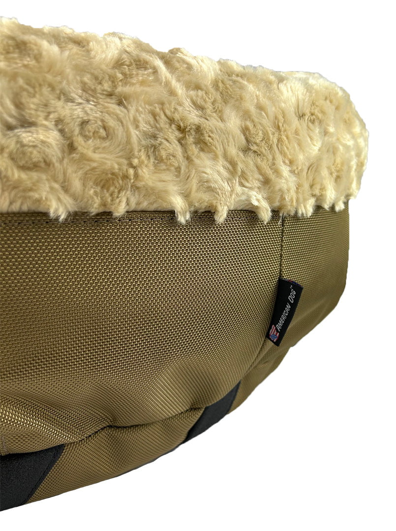 Close-up of a round bolster bed showing cream plush top over camel woven fabric base