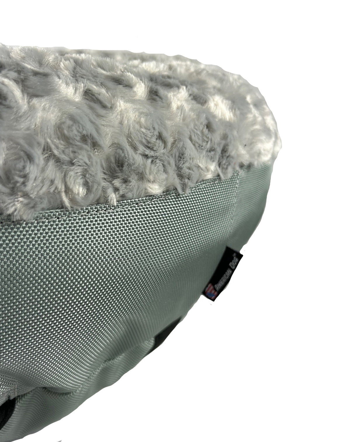 Close-up of a round bolster bed showing silver gray plush fur top over gray fabric base