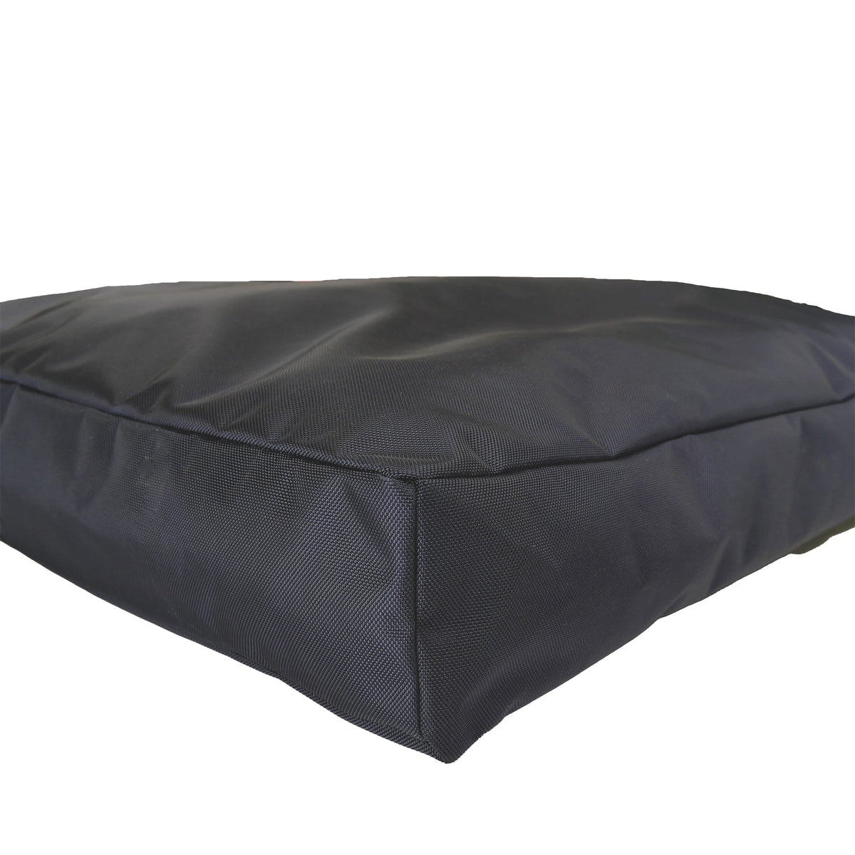 Corner close-up of a black rectangular Armor dog bed showing ballistic weave fabric