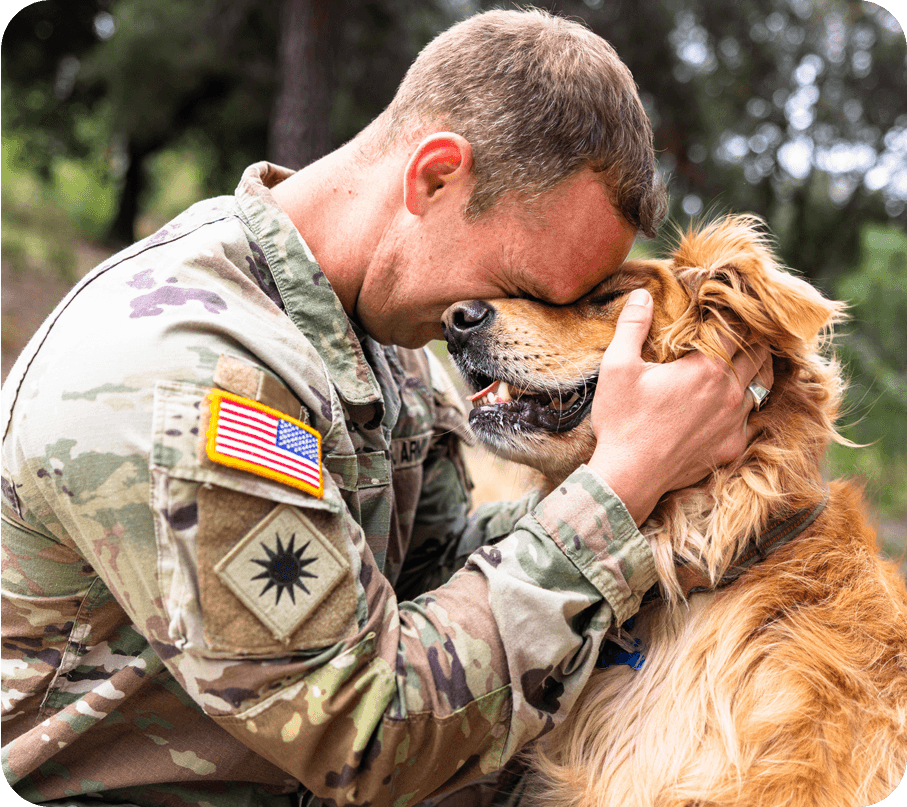 Soldier in uniform kissing a dog outdoors